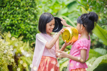 Obraz premium Songkran day with thai girls children playing splash water in songkran festival with thai period dress