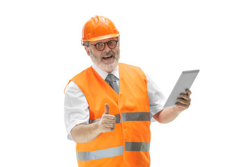 The builder in a construction vest and orange helmet standing with tablet on white studio background. Safety specialist, engineer, industry, architecture, manager, occupation, businessman, job concept