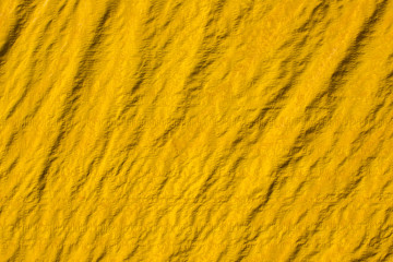 old yellow crumpled canvas with folds and shadows. rough surface texture