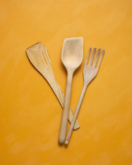 Wooden kitchen utensils on a bright yellow background