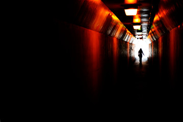 Person walking through tunnel towards light at end. Accomplishing goal or leaving darknenss for...