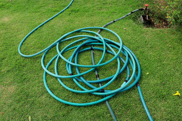 a green hose lying on the grassy ground, A close up image of a garden hose, Rubber tube for...