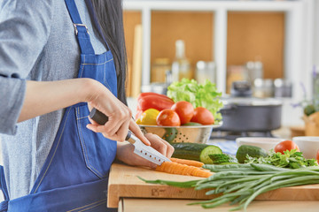 A young woman prepares food in the kitchen. Healthy food - vege