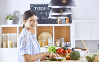 A young woman prepares food in the kitchen. Healthy food - vege