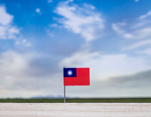 Flag of Taiwan with vast meadow and blue sky behind it.
