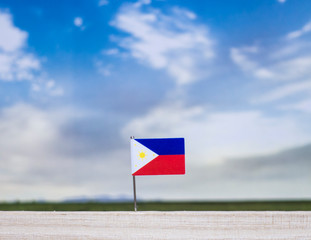 Flag of Philippines with vast meadow and blue sky behind it.