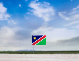 Namibia flag with vast meadow and blue sky behind it.