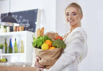 Young woman holding grocery shopping bag with vegetables Standi