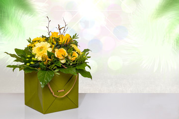 Close-up of a beautiful bouquet with yellow flowers in a decorative green gift box on a bright table over abstract spring landscape isolated on a white background. Macro. Space for design.