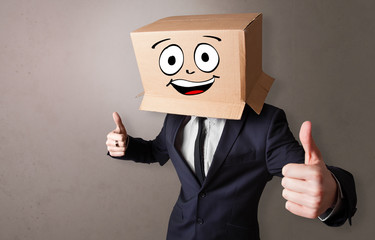 Young boy standing and gesturing with a cardboard box on his head
