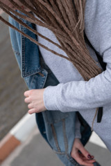 Close-up. Girl with dreadlocks in a sweatshirt and jeans walk the street