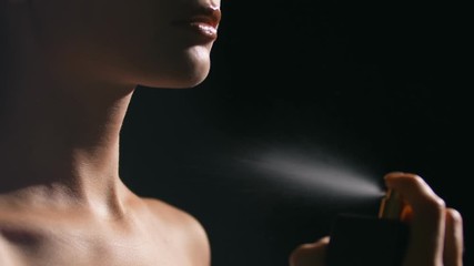 Young woman spraying perfume on her neck