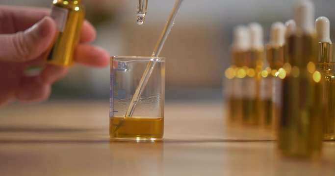 Close up of perfumer adding essential oil into alcoholic mixture