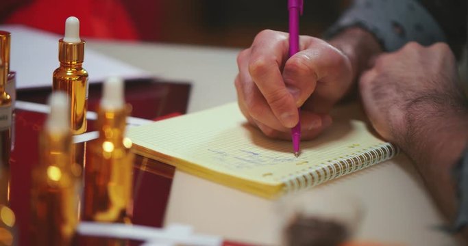 Close up of man writing down perfume composition