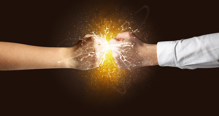 Obraz na płótnie Canvas Two hands fighting with orange dust, spark, glow and smoke concept 