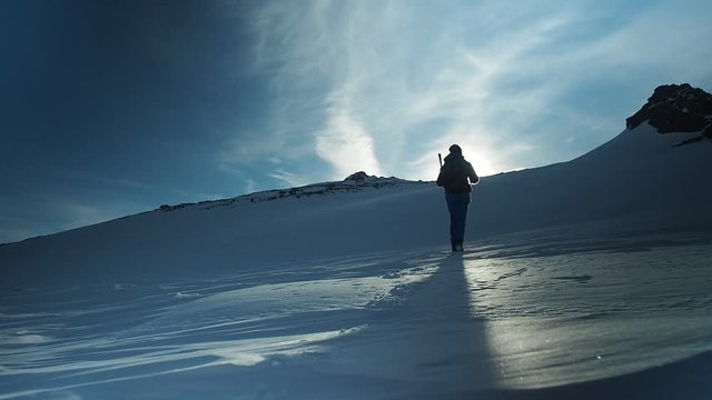 Hiker with backpack climbing top of mountain, mountaineering concept. Man walking snow, hiking in winter. Trekking adventure, people in nature concept. Epic sunset view snow mountain landscape,