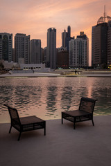 evening view of Empty chairs near water pool agianst abu dhabi city scpae