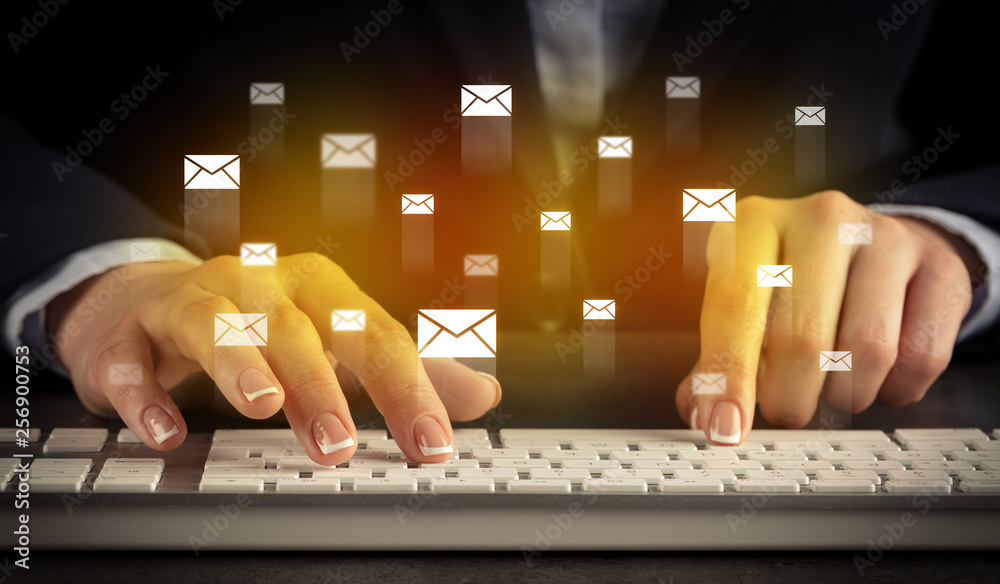 Wall mural Business woman typing on keyboard with mail icons around
