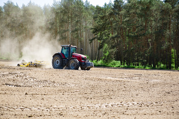 Fototapeta Traktor orzący pole pod zasiew, prace w polu na wiosnę obraz