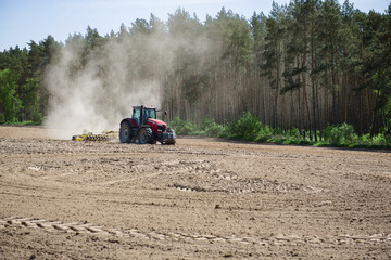 Traktor orzący pole na wiosnę. Przygotowywanie pola pod zasiew zboża.