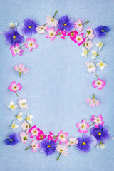 Beautifuil, natural frame with violet pansies and pink roses on blue, fabric background