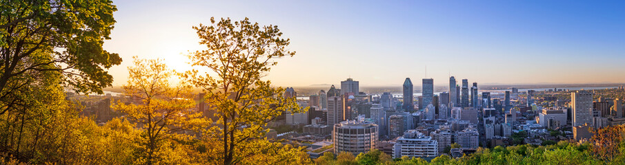 Amazing view of Montreal city at sunrise with colorful blue architecture, green and yellow landscape. Beautiful sky and sun light over Montreal downtown skyline in morning time. Magic Canadian city.