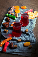 Fruit tea in turkish glasses,  oriental sweets, dates and dried apricots. Top view kitchen table