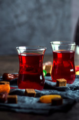 Raspberry tea in turkish glasses, dates, dried apricots. Close-up, low key