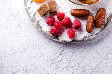 Raspberries, cane sugar cubes and dates on a wooden tray. Vegetarian snack and dessert concept