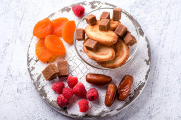Raspberries, dates, dried apricots, cane sugar and cookies on a wooden board. Delicious and healthy vegetarian dessert