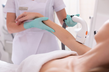 Obraz premium Careful beautician holding hand of woman at the hair removal