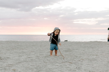 Portrait of Cute Little Baby Boy Child Playing and Exploring in the Sand at the Beach During Sunset Outside on Vacation in Hoodie Zip-Up Sweat Shirt