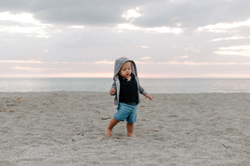 Portrait of Cute Little Baby Boy Child Playing and Exploring in the Sand at the Beach During Sunset Outside on Vacation in Hoodie Zip-Up Sweat Shirt