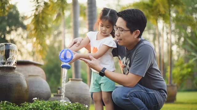 Lift up-down shot : Asian Man With  little Girl Is Watering in garden at home.