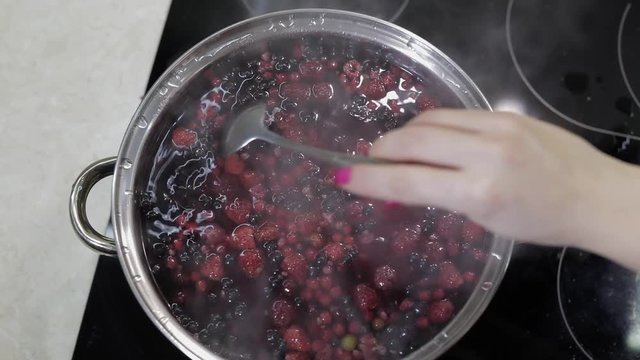 Stir the berries in pot with boiling water. Cooking compote. Kitchen