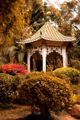 Chinese gazebo on the background of beautiful nature with a side of bright pink flower bed