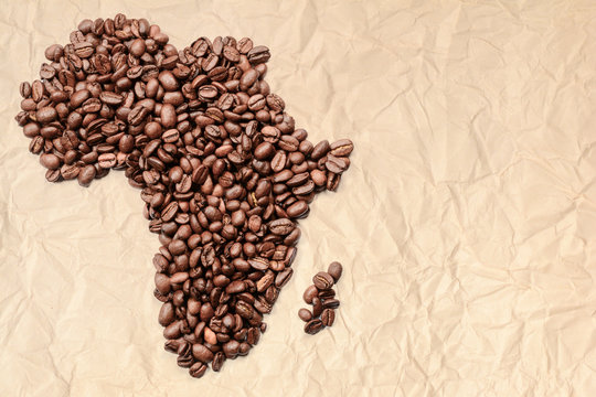 Whole bean coffee. The contour of the mainland of Africa is made of coffee beans on old crumpled paper