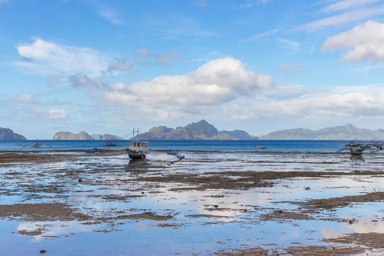 Scenic tropical landscape. Low tide on seashore. Panorama seascape with traditional philippinian fishing boats. Philippines, island Palawan, El Nido beach. Tropical vacation and tourism. Blue lagoon. 