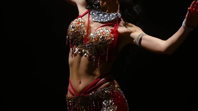 Girl performs belly dance in oriental costume. Black background. Slow motion. Close up