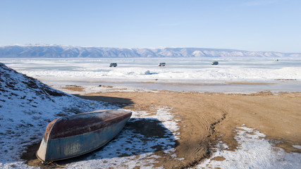 Olkhon island in winter: on the shore is an inverted old dilapidated boat on the ice in the...