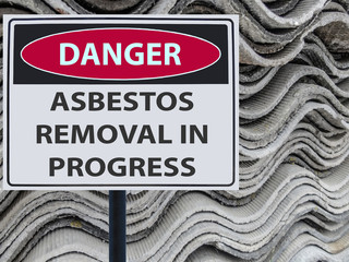 sign danger asbestos removal in progress and a stack of sheets roof of asbestos.