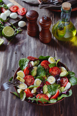 Delicious salad with cherry tomatoes, avocado, herbs, quail egg  pieces in a salad bowl on a wooden table, vertical