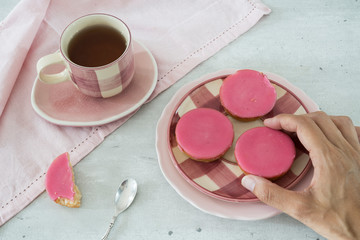 cup of tea with typical Dutch cake with pink frosting on plate. 