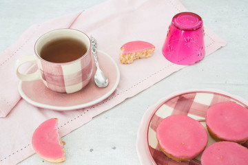 cup of tea with typical Dutch cake with pink frosting on plate. 