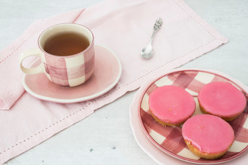 cup of tea with typical Dutch cake with pink frosting on plate. 