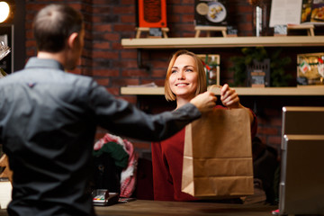 Picture of girl seller with paper bag and man shopper from back