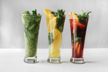 Three glasses of different cocktails with mint, orange,lime on white background indoor.