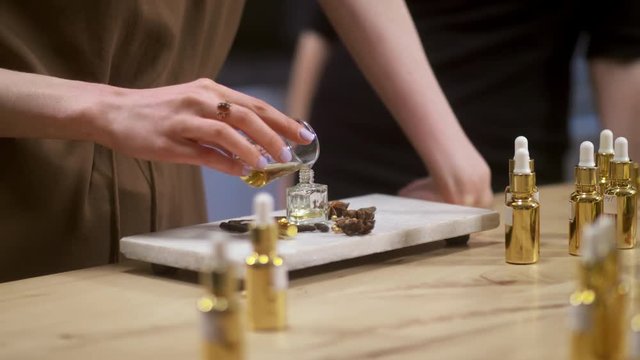 Close up of woman pouring perfume in bottle