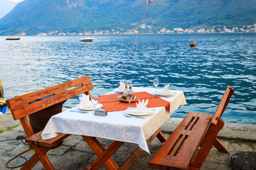 Reserved table with a white tablecloth, glasses and plates for a romantic dinner in a restaurant on the beach on vacation. Celebration. Party. Travel. Catering