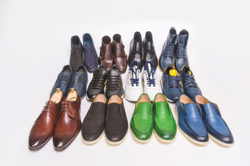 Multicolored men's shoes on a white background. A lot of men's shoes in a row. Types of male shoes. Boots, sneakers and shoes